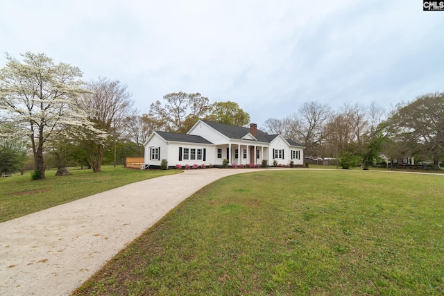 view of front of property with a chimney, a front yard, and concrete driveway