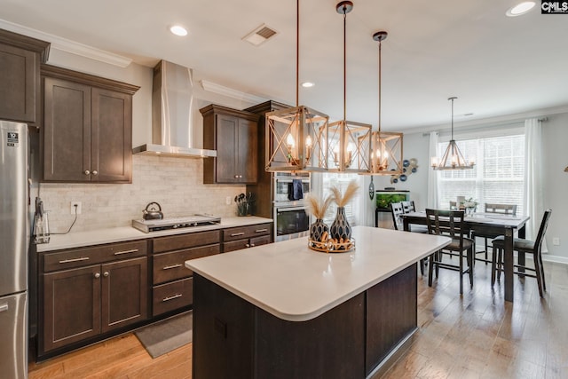 232 Compass Trl, Blythewood, SC 29016 - kitchen featuring wall chimney range hood, visible vents, appliances with stainless steel finishes, decorative backsplash, and a notable chandelier