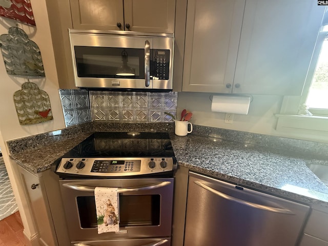 kitchen featuring dark stone counters, decorative backsplash, wood finished floors, and stainless steel appliances