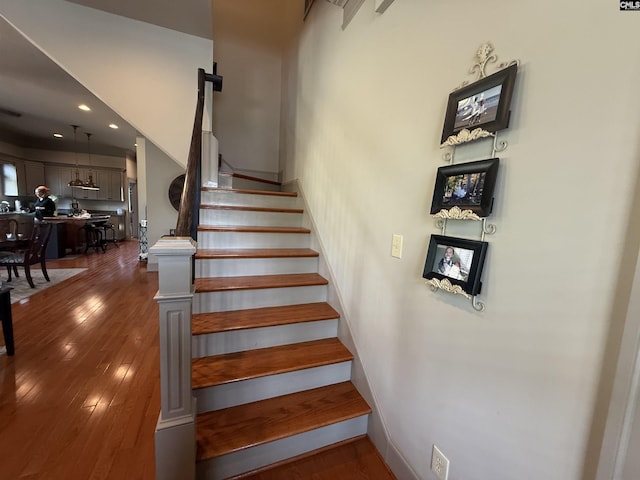 staircase featuring hardwood / wood-style floors, baseboards, and recessed lighting