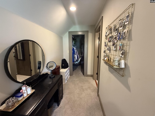 hallway with baseboards, light colored carpet, and vaulted ceiling