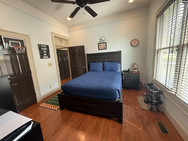 bedroom featuring wood finished floors, ceiling fan, baseboards, and visible vents