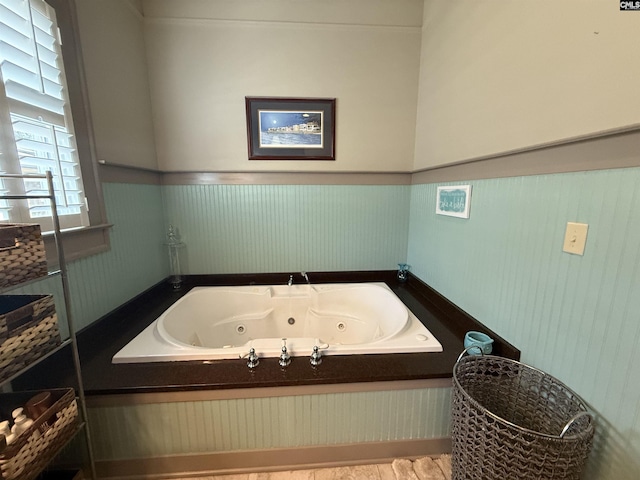 full bath with a whirlpool tub and wainscoting