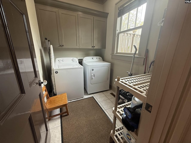 washroom with light tile patterned floors, washing machine and dryer, and cabinet space