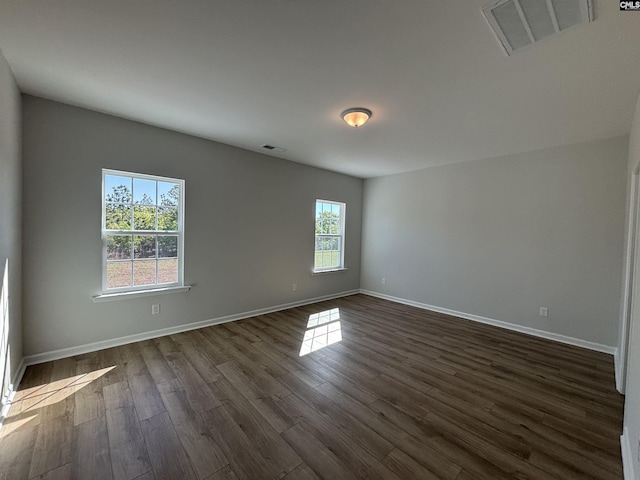 spare room featuring visible vents, dark wood-style flooring, and baseboards
