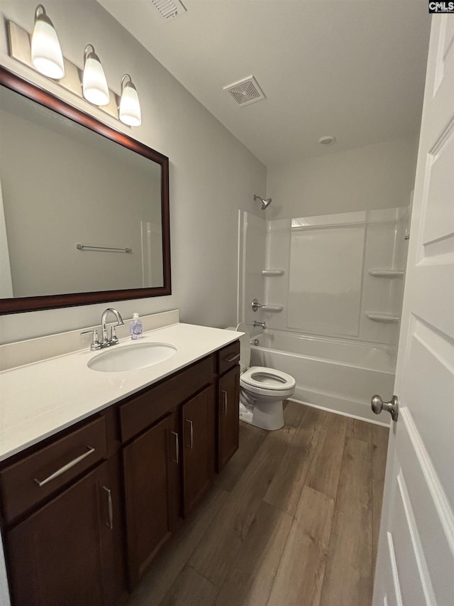 bathroom featuring visible vents, shower / bathtub combination, toilet, wood finished floors, and vanity