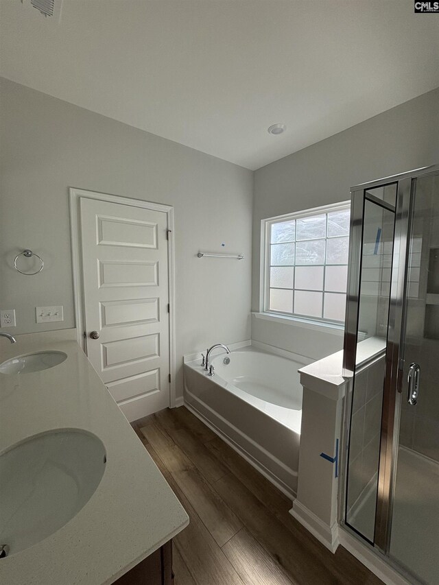 bathroom featuring wood finished floors, a shower stall, a garden tub, and a sink