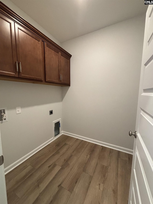 clothes washing area featuring hookup for an electric dryer, cabinet space, baseboards, and dark wood finished floors
