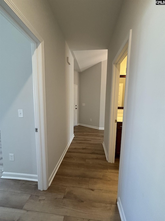 corridor with baseboards and wood finished floors