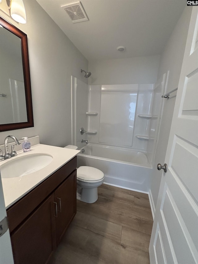full bath featuring wood finished floors, visible vents, toilet, shower / washtub combination, and vanity