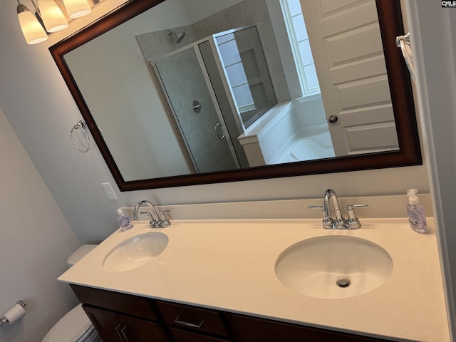 full bathroom featuring double vanity, toilet, a shower stall, and a sink