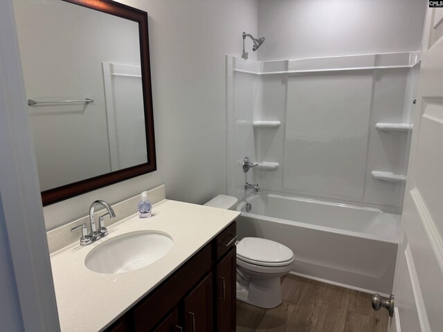 bathroom featuring wood finished floors, toilet, shower / tub combination, and vanity