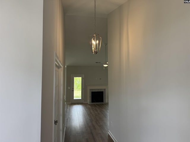 hallway featuring a chandelier, baseboards, dark wood-style flooring, and a towering ceiling
