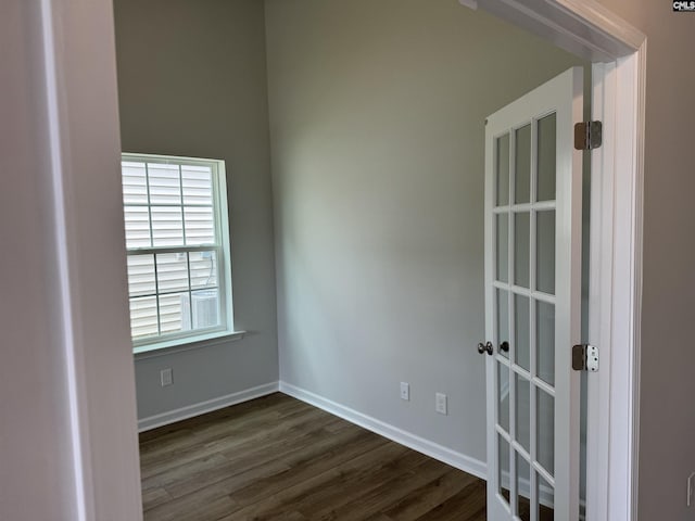 unfurnished room with baseboards and dark wood-type flooring