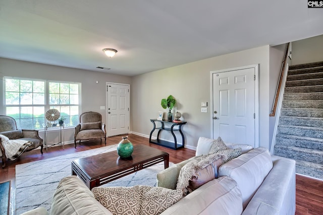 living area featuring wood finished floors, baseboards, visible vents, and stairs