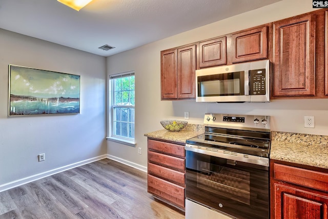 kitchen with baseboards, light stone countertops, visible vents, appliances with stainless steel finishes, and light wood finished floors