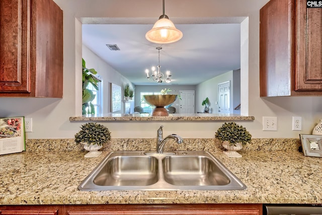 kitchen with visible vents, a sink, a chandelier, dishwashing machine, and brown cabinets