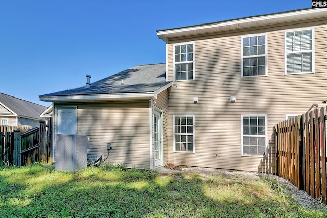 back of property with fence and a lawn