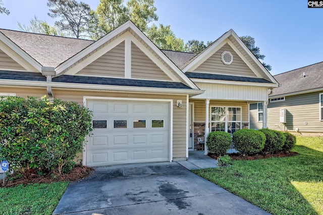 view of front of property featuring an attached garage, a shingled roof, a front yard, and driveway