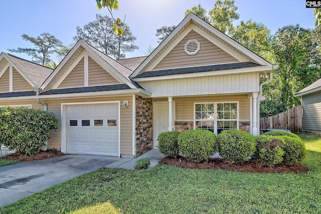 view of front of home featuring a front yard, an attached garage, stone siding, fence, and driveway