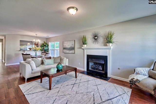living area with a fireplace, baseboards, an inviting chandelier, and wood finished floors