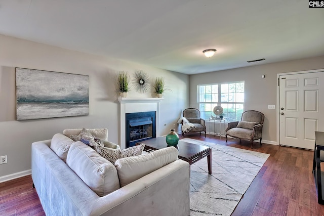 living area with wood finished floors, visible vents, a fireplace, and baseboards