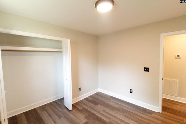 unfurnished bedroom featuring a closet, baseboards, dark wood-style floors, and visible vents