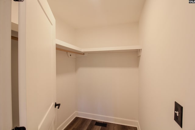 clothes washing area featuring visible vents, dark wood-style flooring, and baseboards