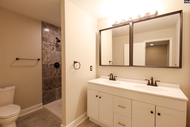 bathroom featuring tiled shower, double vanity, a sink, and toilet