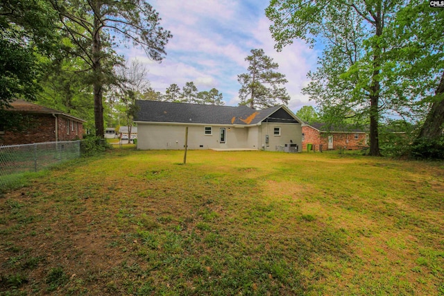 rear view of house with fence and a lawn
