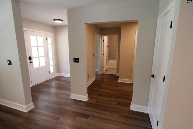 hall featuring dark wood-type flooring and baseboards