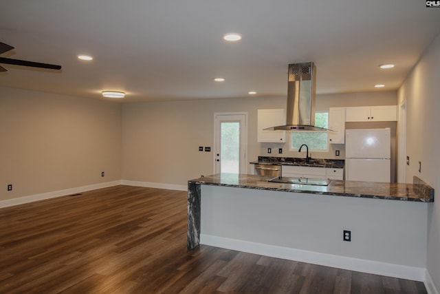 kitchen featuring freestanding refrigerator, dark wood finished floors, white cabinetry, dark stone counters, and island exhaust hood