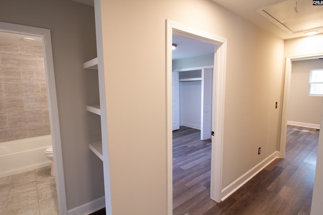 corridor with wood finished floors, attic access, and baseboards