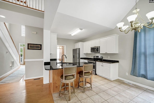 124 Pond Edge Ln, Chapin, SC 29036 - kitchen with a notable chandelier, a kitchen breakfast bar, white cabinetry, visible vents, and appliances with stainless steel finishes