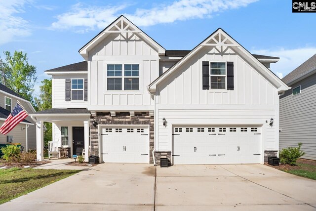 view of front of house featuring board and batten siding, driveway, an attached garage, and stone siding