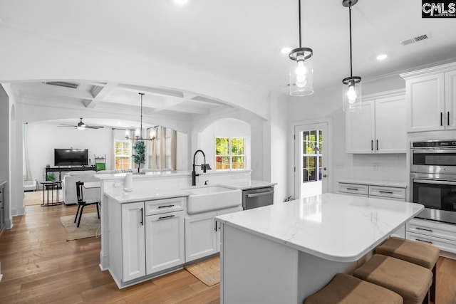 kitchen with a sink, visible vents, stainless steel appliances, open floor plan, and a center island with sink