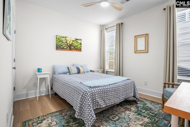 bedroom with ceiling fan, wood finished floors, and baseboards