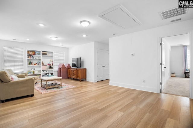 living room with visible vents, light wood-type flooring, attic access, and recessed lighting