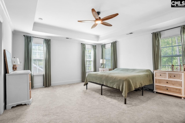 bedroom with carpet floors, baseboards, visible vents, crown molding, and a tray ceiling