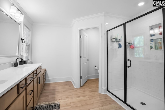 bathroom featuring a sink, a stall shower, baseboards, ornamental molding, and wood finished floors