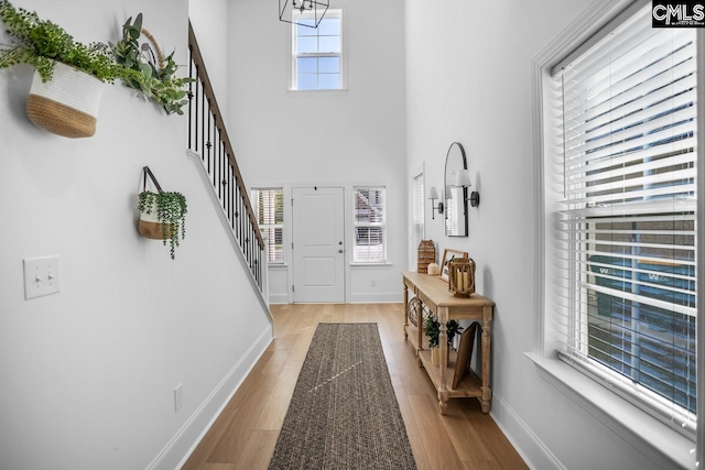foyer entrance featuring stairway, light wood-style flooring, and baseboards