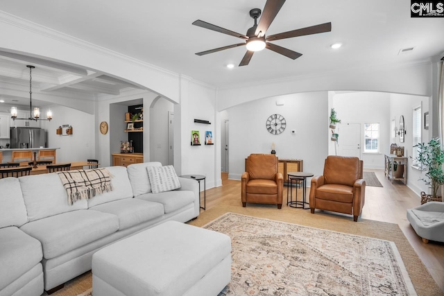 living area featuring recessed lighting, arched walkways, ceiling fan with notable chandelier, and crown molding