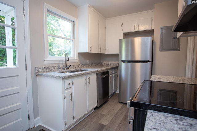 kitchen with light wood-style floors, white cabinetry, appliances with stainless steel finishes, under cabinet range hood, and a sink