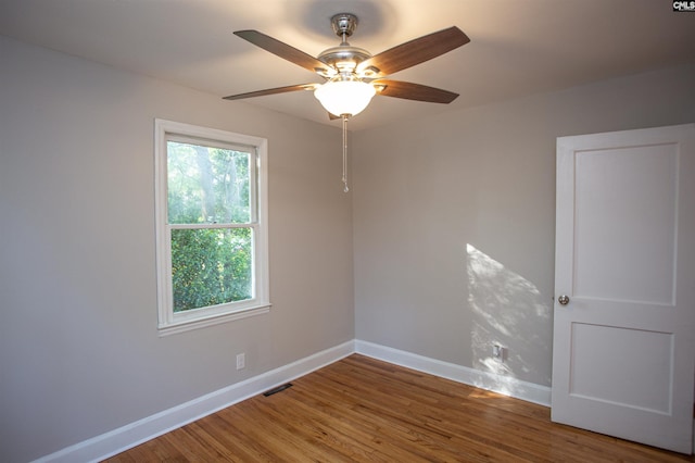 spare room featuring visible vents, baseboards, a ceiling fan, and wood finished floors