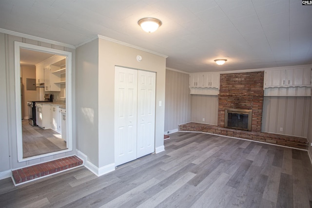 unfurnished living room featuring a fireplace, baseboards, ornamental molding, and wood finished floors