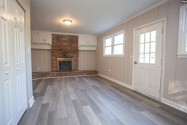 unfurnished living room featuring crown molding, wood finished floors, baseboards, and a large fireplace