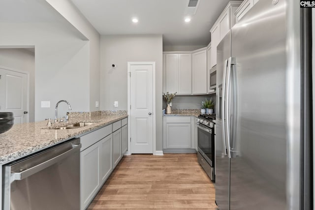 1071 Cornelia St, Elgin, SC 29045 - kitchen featuring visible vents, a sink, light wood finished floors, stainless steel appliances, and light stone counters
