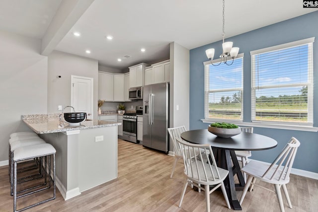 1071 Cornelia St, Elgin, SC 29045 - kitchen featuring a breakfast bar, a peninsula, white cabinetry, stainless steel appliances, and light wood finished floors