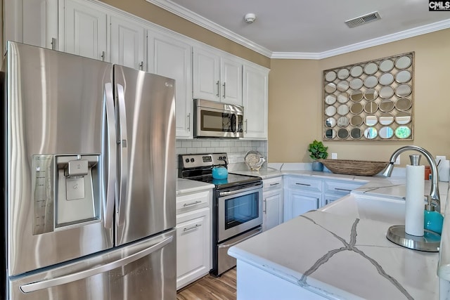 209 Mariannas Ct, Lexington, SC 29072 - kitchen featuring crown molding, a peninsula, white cabinetry, visible vents, and appliances with stainless steel finishes