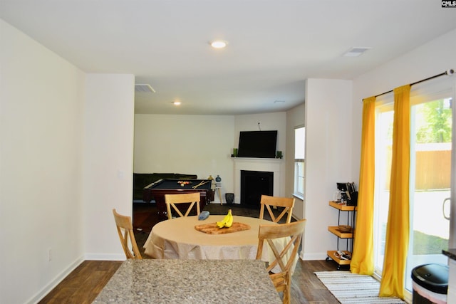 dining room featuring dark wood-style flooring, baseboards, and a fireplace